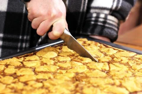 The hand is cutting the cake. Cake on a baking sheet Stock Photos