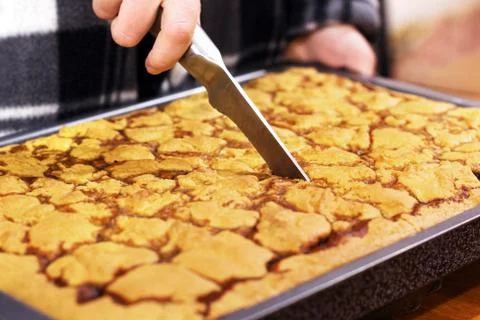The hand is cutting the cake. Cake on a baking sheet Fotos de archivo
