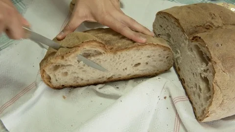 Hand cutting fresh bread on Flax tablecloth Stock Footage 77839297