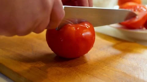Hand cutting a fresh red tomato on wooden board Stock Footage 333876428