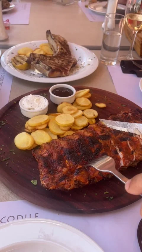 Hand Cutting Grilled Meat with Knife on Serving Plate Stock Footage 314984409