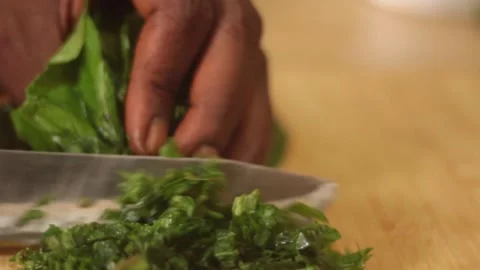 Hand cutting leafy green vegetable on wooden chopping board Stock Footage 304663186