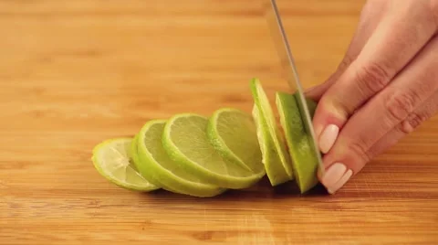 A hand is cutting a lime with a silver knife in slices. Stock Footage 57213125