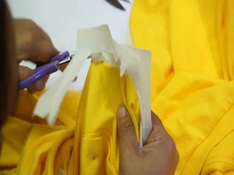 Hand cutting lining paper on yellow t-shirt Stock-Footage 99629019