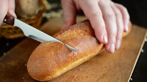 Hand cutting loaf of bread with knife. Slice of bread on the wooden board. Stock Footage 113998886