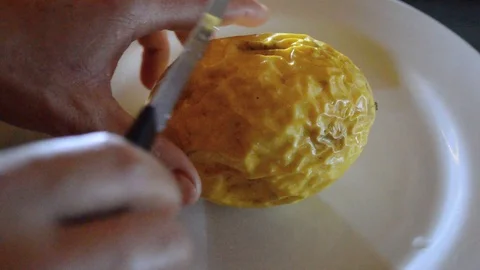 Hand cutting passion fruit in half on a white plate Stock Footage 115372418