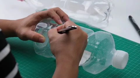 Hand cutting a plastic bottle with a cutter to grow plants or vegetables inside. Stock Footage 248750819