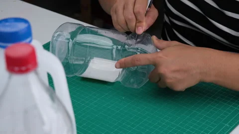 Hand cutting a plastic bottle with a cutter to grow plants or vegetables inside. Stock Footage 248750898