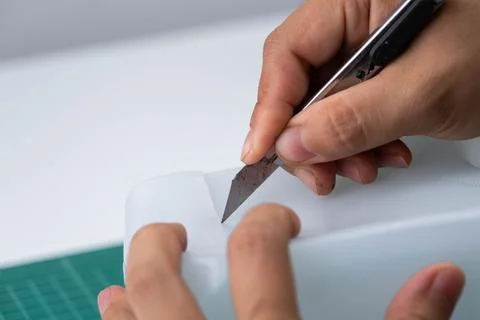 Hand cutting a plastic bottle with a cutter to grow plants or vegetables inside. Stock Photos