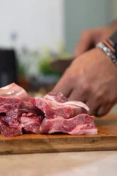 Hand cutting raw lamb chops on wooden board Stock Photos