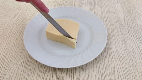Hand Cutting Semi Hard Cheese on White Plate over Wooden Surface Stock Footage 325078009