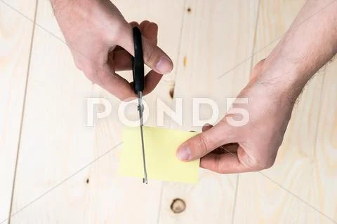 Hand is cutting a sheet of yellow paper Stock Photos