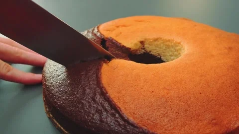 Hand Cutting a Two-Tone Round Cake on Indoor Kitchen Surface Stockbeeldmateriaal 342874851