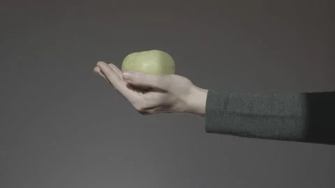 A hand on a dark background holds out a green apple in the palm of your hand. Le Stock Footage 233001101