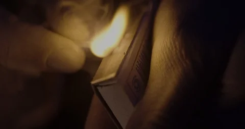 Hand in the dark, lights a match on a matchbox to shoot in slow motion Stock Footage 123502989