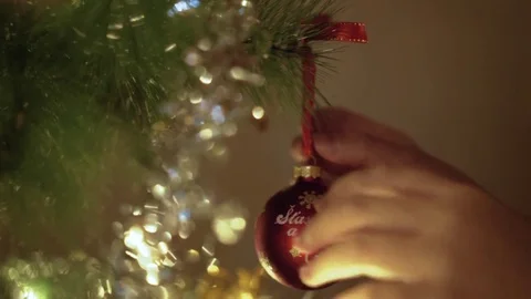Hand decorating Christmas tree with red ball. Hanging decorations on tree Stockbeeldmateriaal 81659945