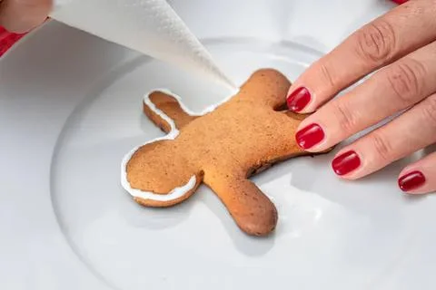 Hand decorating gingerbread cookie on white plate Stock Photos