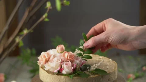 Hand is decorating a raw mousse cake with tenderness pink flowers and leaves Stock Footage 196222398