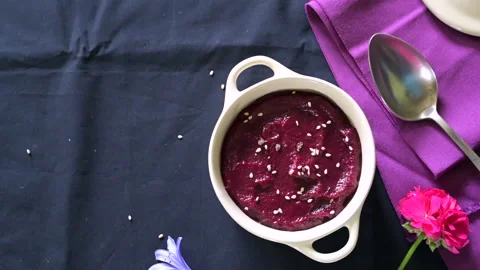 Hand decorating a small casserole with beet cream with sesame seeds Stock Footage 202614532