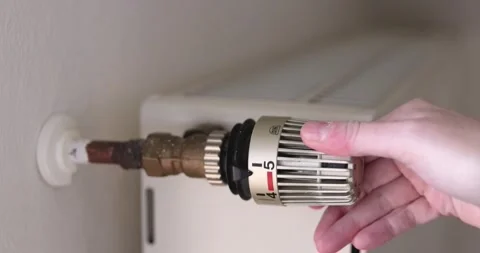 Hand decreasing the temperature control of a white radiator of a central heating 库存影片 228041586