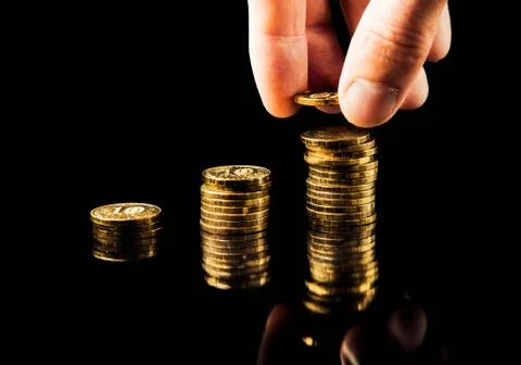 Hand deliver a stack of coins graph profit growth on black background Stock Photos