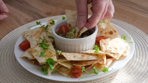 Hand dipping crispy chips into fresh guacamole  video Vídeos de archivo 333036778