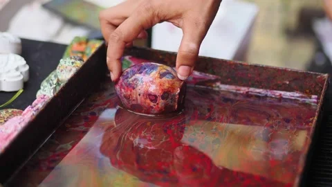 Hand dipping egg in colorful paint at art event Stock Footage 340303531