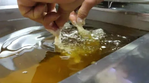 Hand dipping fresh battered prawns into hot boiling oil in a commercial deep fry Video stock 343028941