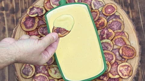 Hand dipping Peruvian purple potato chips served with Huancaina chili sauce Video stock 341440540