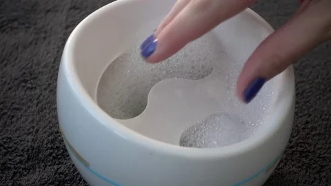 Hand dipping into a portable nail spa. Stock Footage 78933174