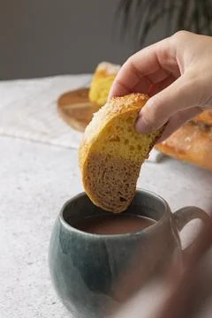 Hand dipping slice of sweet bread into cup of hot chocolate for delicious b.. Stock Photos
