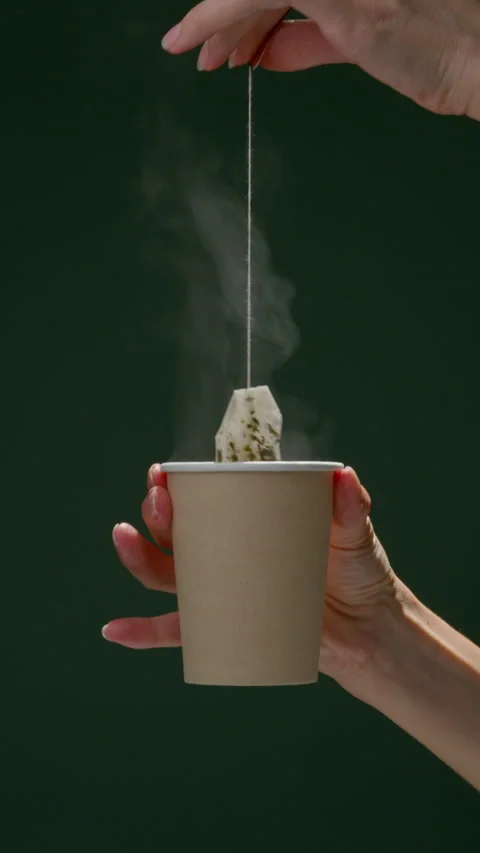 Hand dipping tea bag in paper cup to brew faster Video stock 306168275