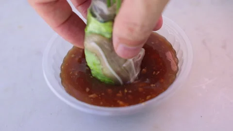 Hand dipping vietnamese spring roll into peanut sauce Stock-Footage 337360349