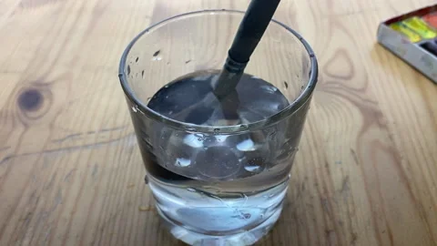 A hand dips a brush with paint into a glass. Stock Footage 234426394