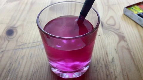 A hand dips a brush with pink paint into a glass. Stock Footage 234426100