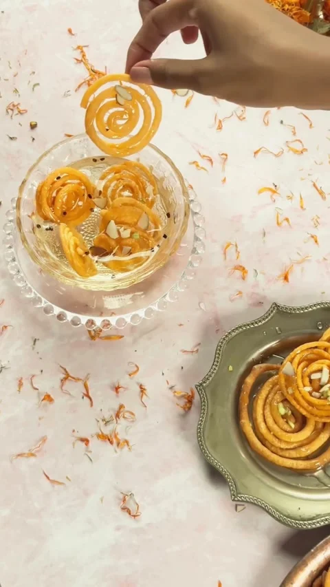 Hand dips crispy orange jalebi into sweet sugar syrup Vídeos de archivo 331773195