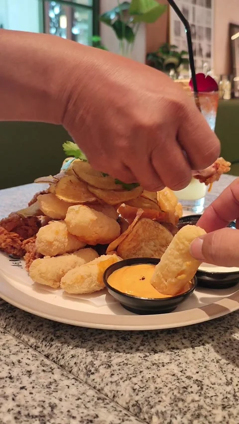 Hand dips crispy snack into vibrant orange sauce Stock Footage 340531236