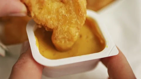 Hand dips a fried piece of chicken nuggets into sauce Stock Footage 196627342