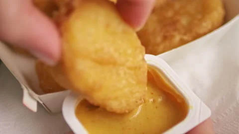 Hand dips a fried piece of chicken nuggets into sauce. Stock Footage 196631856
