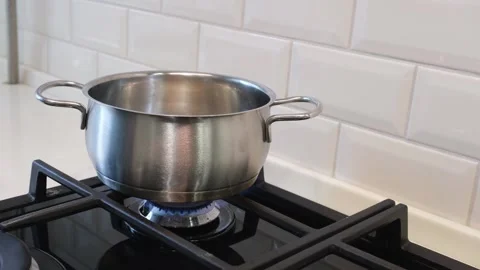 Hand dips pasta into boiling water in a pot on a gas burner Stock Footage 231409077