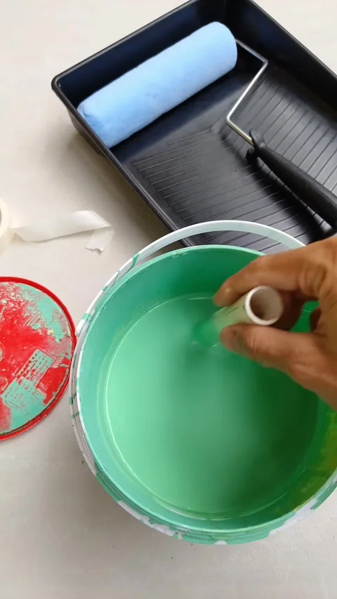 Hand dips roller into vibrant green paint Stock Footage 331562276