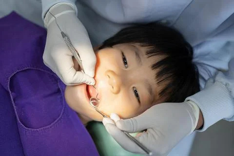 Hand of Doctor dentist is working on the teeth of asian little kid 6 year old Stock Photos