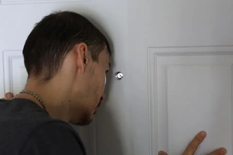 Hand on door while man looks through peephole security concept Stockfoto's