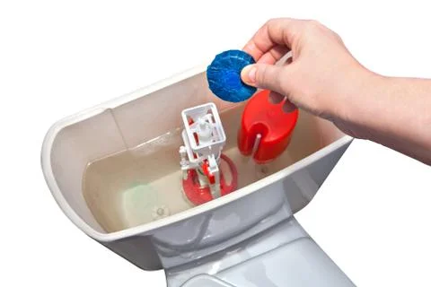 Hand down the lower cleaning tablet in the toilet cistern, close-up. Stock Photos