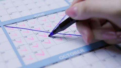 Hand drawing a diagonal purple line across a calendar page in a close-up view. Stock Footage 305157917