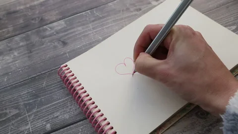 Hand drawing a heart on a notebook Stock Footage 148224967