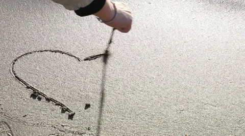 A hand drawing a heart on the sand Stock Footage 10713698