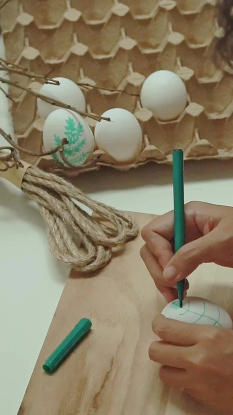 Hand drawing a leaf pattern on a white egg using green marker pen in a creative  Stock Footage 307047213