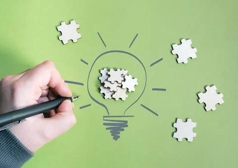 Hand Drawing Light Bulb with Puzzle Pieces on Green Background Stock Photos