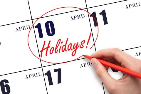Hand drawing a red circle and writing the text Holidays on the calendar date  Stock Photos